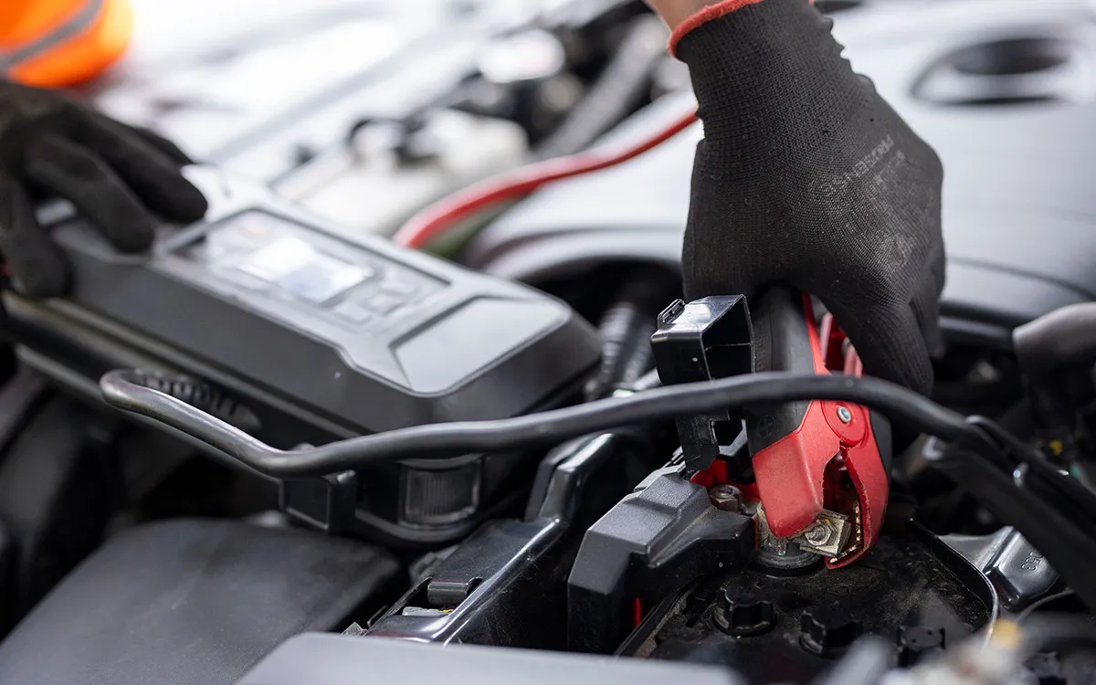 AMI Roadside Rescue technician fitting a new car battery at a customer's home.