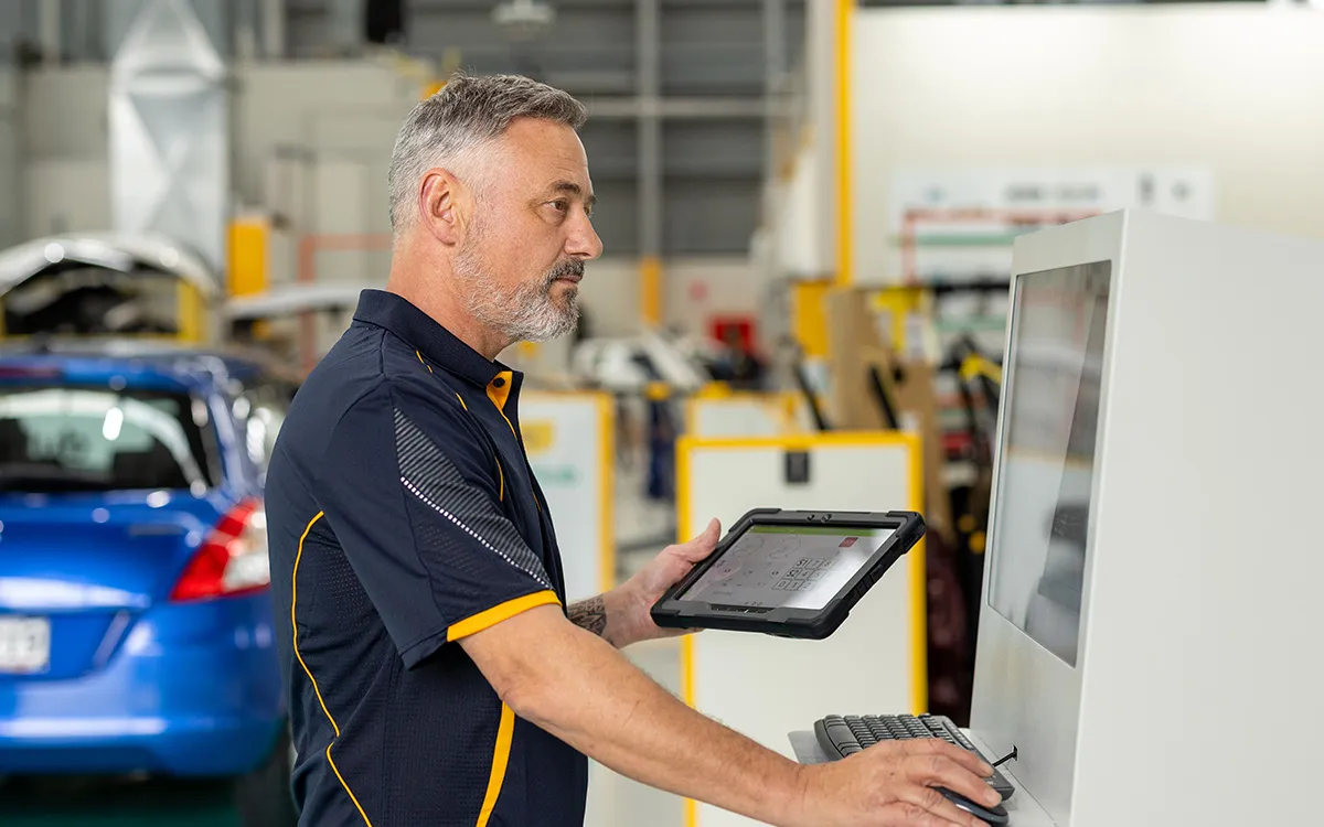 AMI MotorHub technician running a computer diagnostic scan on a vehicle.