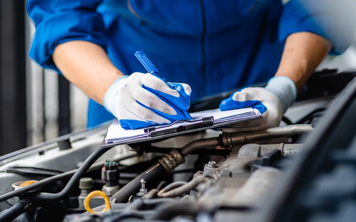 AMI MotorHub technician replacing a radiator hose and topping up engine coolant.