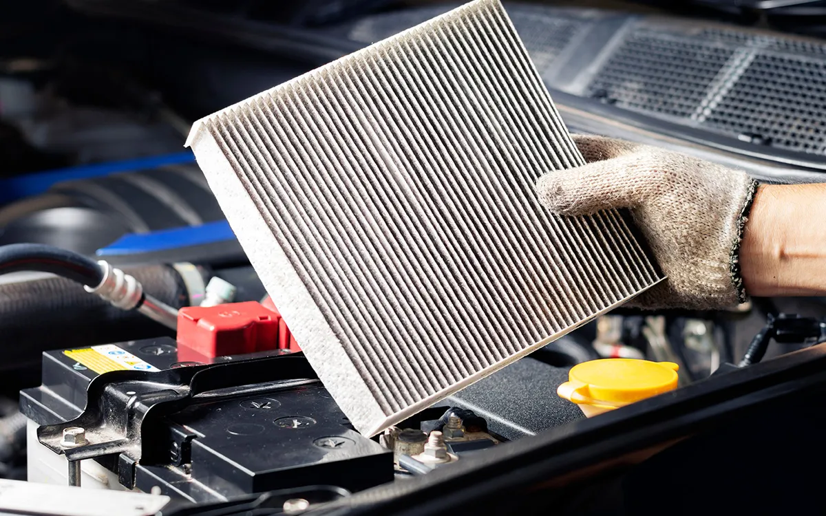 AMI MotorHub technician replacing a cabin air filter during an air-conditioning service.