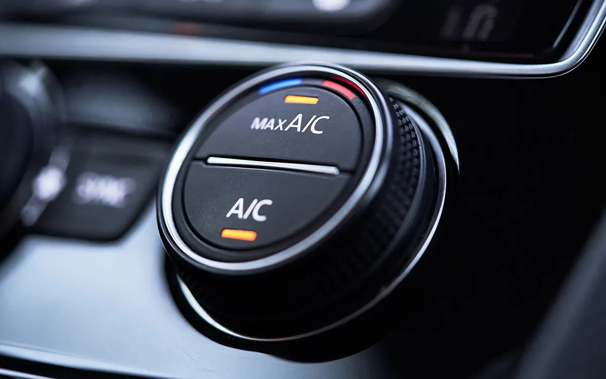 Mechanic connecting an AC manifold gauge to the AC service ports under a car bonnet.